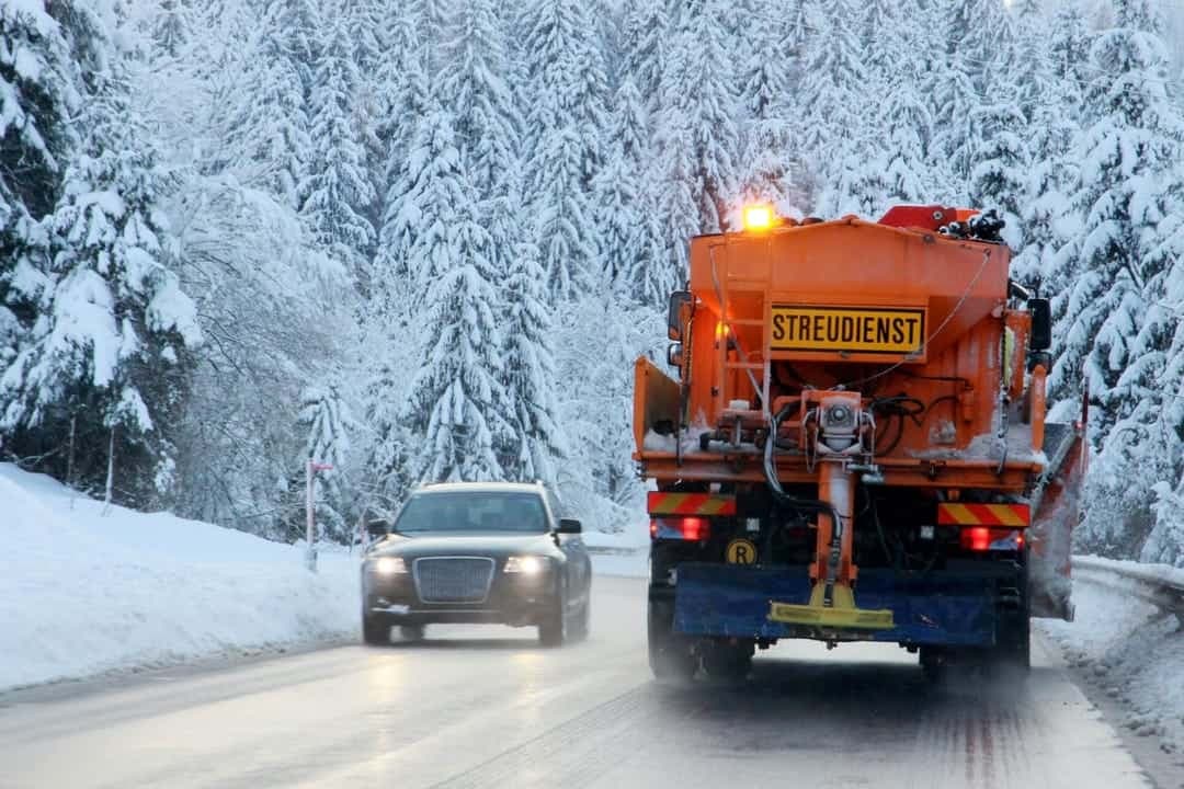 Streudienst-Fahrzeug beim winterlichen Räum- und Streueinsatz auf einer verschneiten Waldstraße